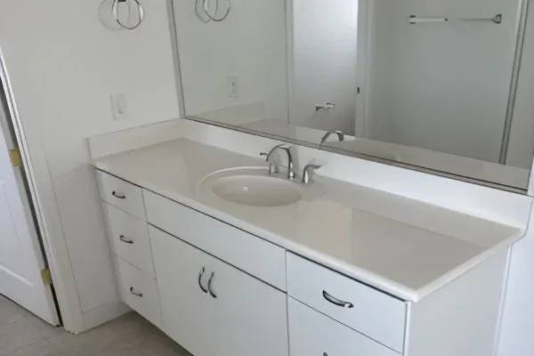 Bathroom vanity with white shaker cabinetry, undermount oval sink, and large mirror