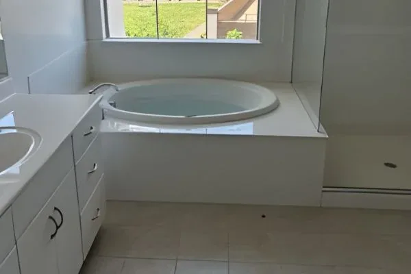 Drop-in oval bathtub with surround tile and bright window light