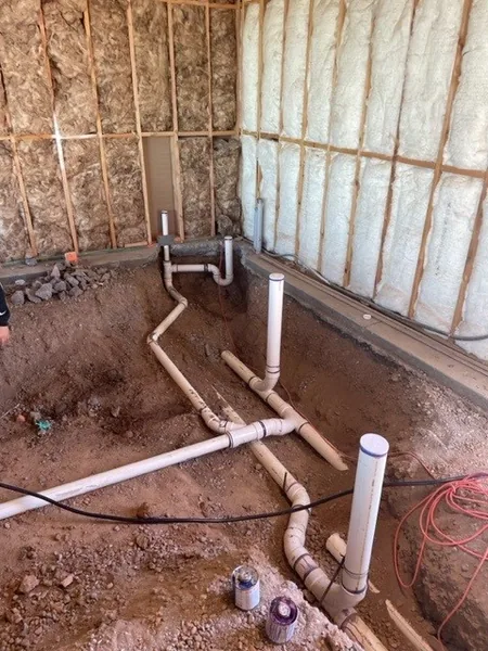 PVC drain pipe layout running through a deep trench between framed walls