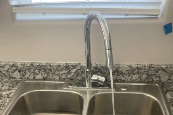 Stainless-steel double-bowl kitchen sink with chrome pull-down faucet on granite countertop