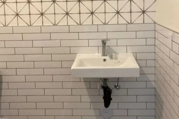 Wall-mount lavatory sink with subway-tile backsplash and patterned accent tile